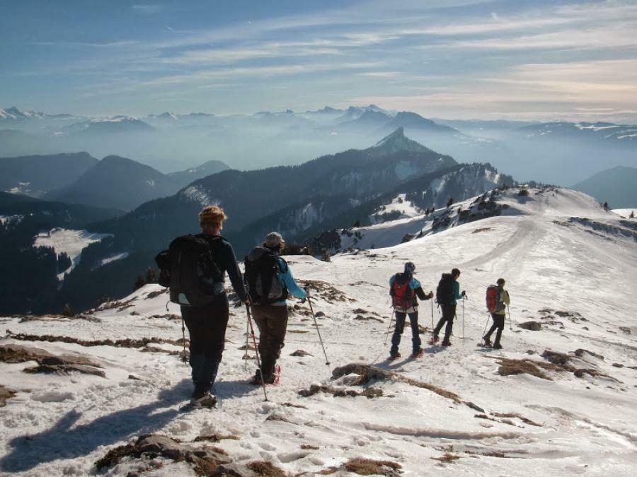 Un groupe de randonneurs progressant sur un sentier enneigé encadré par un accompagnateur